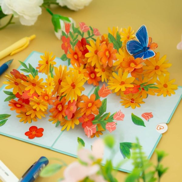 Papercrush pop-up kaart kleurrijke madeliefjes met vlinder kaart uitgevouwen op gele tafel